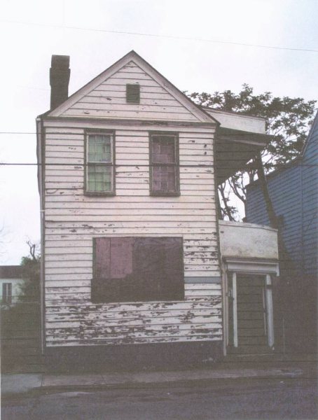 Front facade as found: peeling paint, boarded front window, rotted clapboards.
