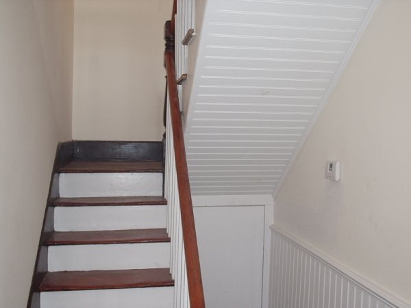 The same stair after restoration: risers painted white, treads stained, beadboard wainscot installed.