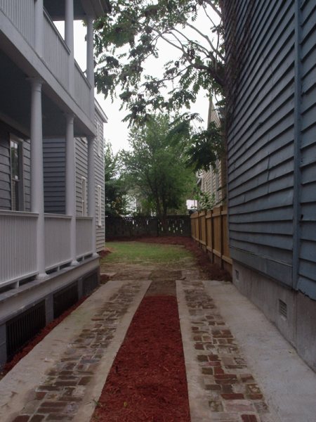 The same alley reborn as a brick walkway with planted beds.